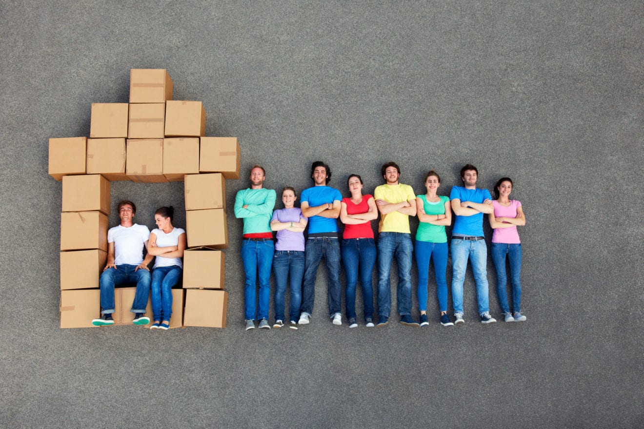 People posing by cardboard box house